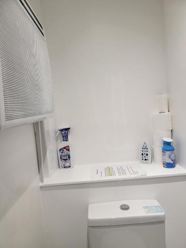 a white bathroom with a white shelf above a toilet at Evabrite Homes in Dartford