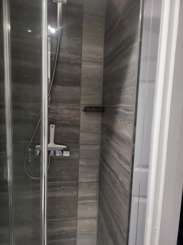 a shower with a glass door with a stool in it at Evabrite Homes in Dartford