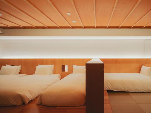 two beds in a room with white sheets at SOKI ATAMI in Atami