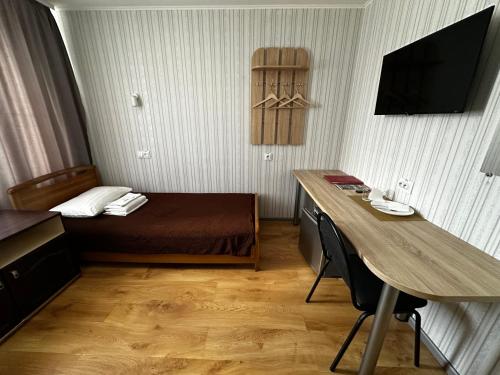 a small hotel room with a bed and a desk at Hotel Almaz in Poltava