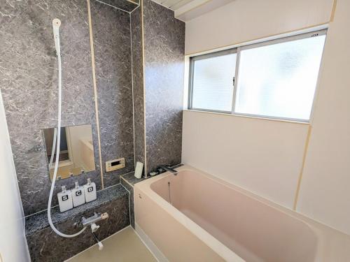 a bathroom with a bath tub and a window at Chateau Sunrise in Tokyo