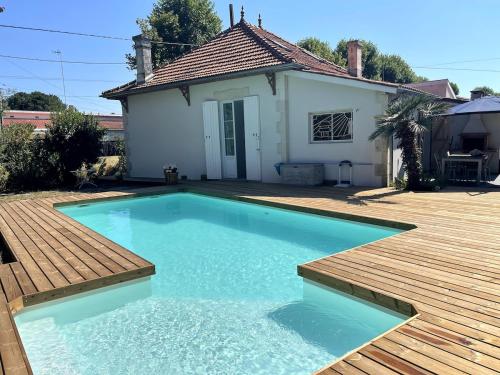 - une piscine en face d'une maison avec une terrasse en bois dans l'établissement La Villa Louise, à Andernos-les-Bains
