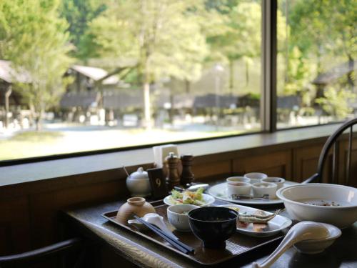 a table with bowls and plates of food and a window at 奥伊勢フォレストピア in Ema