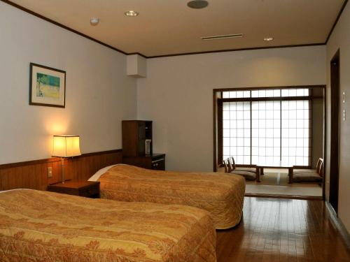 a hotel room with two beds and a window at 奥伊勢フォレストピア in Ema