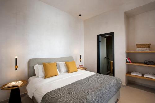 a bedroom with a large bed with yellow pillows at Andromeda Villas & Spa Resort in Imerovigli
