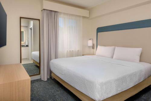 a bedroom with a large white bed and a mirror at Homewood Suites by Hilton Bonita Springs, FL in Bonita Springs