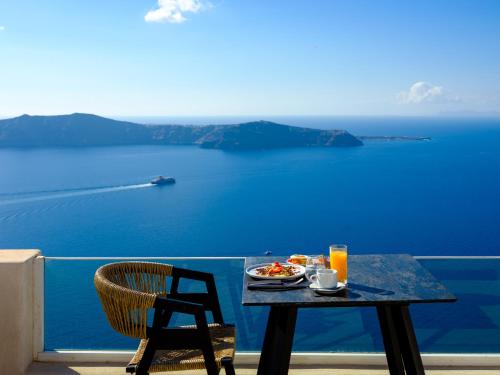 a table and chair with a plate of food on a balcony at Andromeda Villas & Spa Resort in Imerovigli