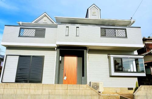 a white house with a orange door and a blue sky at 西戸崎6丁目13番3号 in Fukuoka