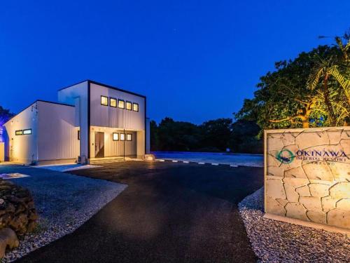 a large building with a stone wall in front of it at 美ら海水族館まで車で3分の好立地ジャグジー付きの1棟貸Suppai Resort Okinawa in Motobu