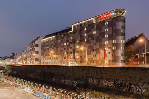 a building with graffiti on it next to a river at Hampton By Hilton Vienna City West in Vienna