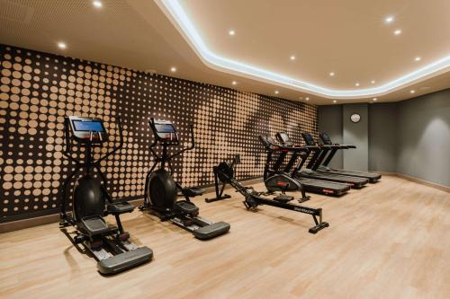 a gym with a row of treadmills and ellipticals at Hampton By Hilton Vienna City West in Vienna