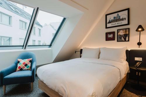 a bedroom with a bed and a blue chair at Hampton By Hilton Vienna City West in Vienna