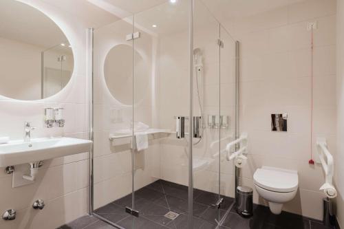 a bathroom with a shower and a toilet and a sink at Hampton By Hilton Vienna City West in Vienna