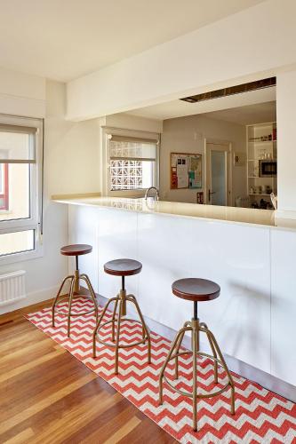 a kitchen with three bar stools on a rug at ATERIAN. SANZ ENEA in Zarautz