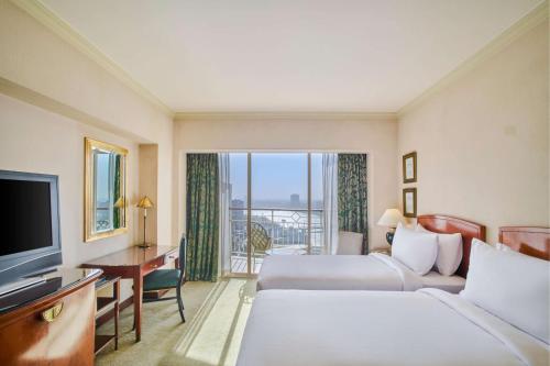 a hotel room with two beds and a television at Hilton Cairo Grand Nile in Cairo