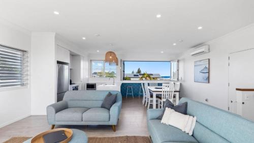 sala de estar con 2 sofás azules y cocina en Boronia Beach House Three, en Sawtell