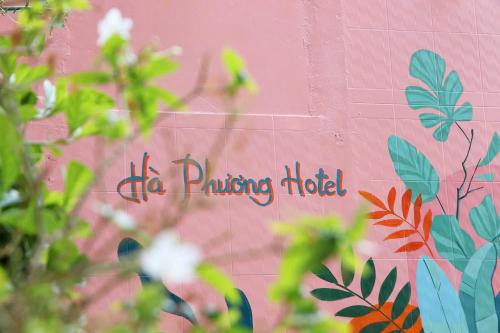 a sign on the side of a pink wall with plants at Ha Phuong Mui Ne Hotel in Mui Ne