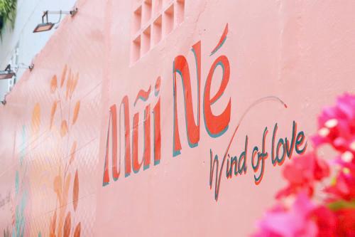 a sign on the side of a pink wall with flowers at Ha Phuong Mui Ne Hotel in Mui Ne