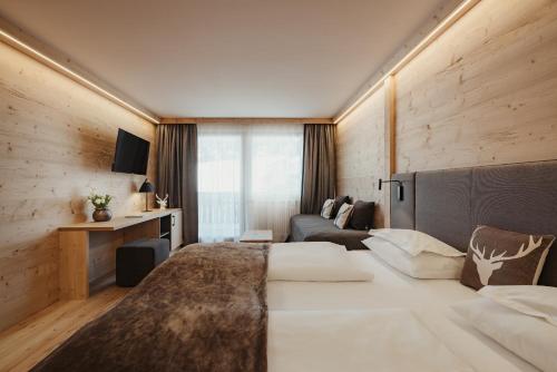 a hotel room with a large bed and a couch at Hotel Antines in La Villa