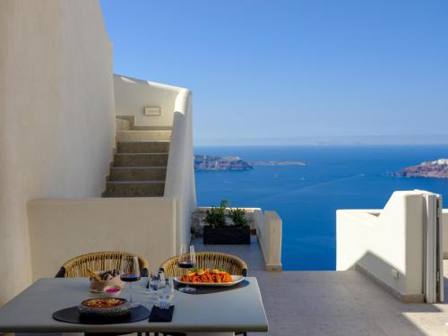 a table and chairs with a view of the ocean at Andromeda Villas & Spa Resort in Imerovigli