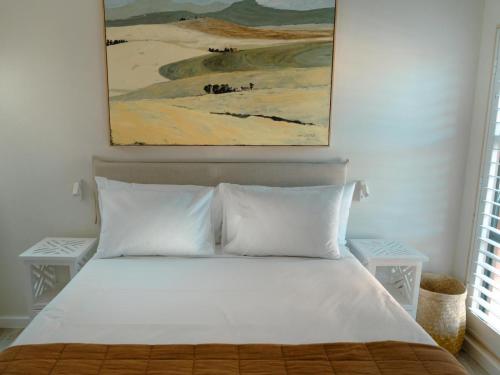 Un dormitorio con una cama blanca con un cuadro encima. en Nook Living, en Riebeek-Kasteel
