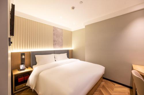 a bedroom with a large white bed in it at Super 8 Hotel Beijing Sanlitun Taikoo Li Branch in Beijing