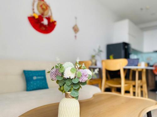 a vase filled with purple and white flowers on a table at Bcons Garden Apartment View Landmark 81 in Dĩ An