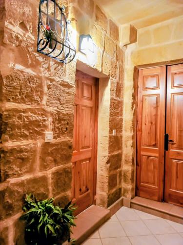 a stone hallway with a wooden door and plants at Mdina Gate Retreat - A charming house of character in Rabat