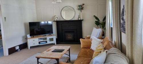 a living room with a couch and a tv and a table at Yellow Pot House in Havelock North