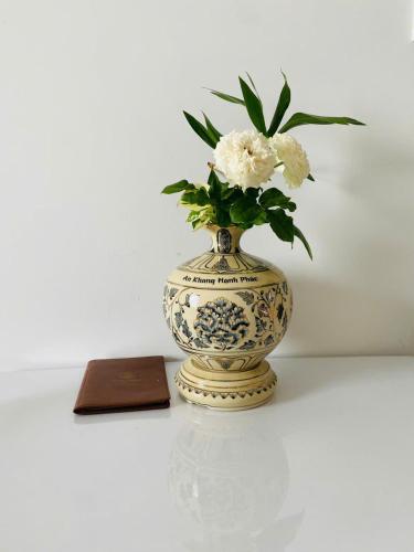 a vase with flowers in it sitting next to a book at Bcons Garden Apartment View Landmark 81 in Dĩ An