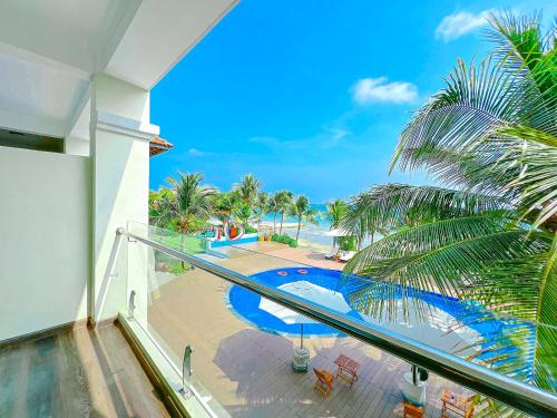 a balcony with a view of a pool and the ocean at Hon Rom 2 Resort in Mui Ne