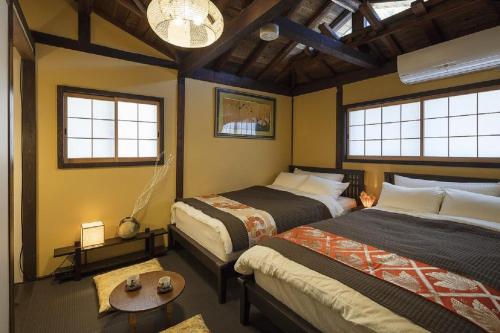 una camera con due letti e un tavolo e due finestre di Kyonoyado Senkakubettei a Kyoto