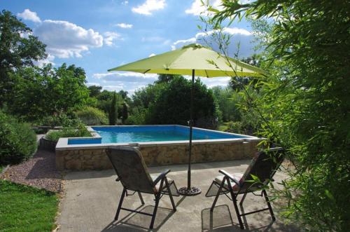 deux chaises et un parasol à côté d'une piscine dans l'établissement Gîte Avec Piscine Sainte Anne, à Ygrande