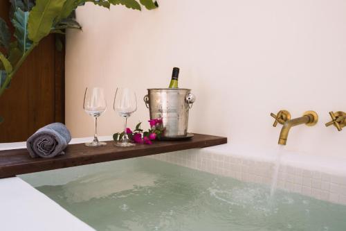 a bathtub with wine glasses and a bucket of water at Le Sen Boutique Hotel in Luang Prabang