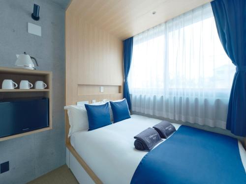 a bedroom with two beds with blue pillows and a window at Sakura Cross Hotel Shinjuku East Annex in Tokyo