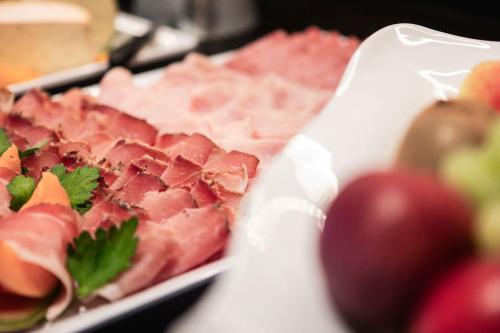 a plate of meat and fruit on a table at Wanderhotel Talblick in San Giacomo