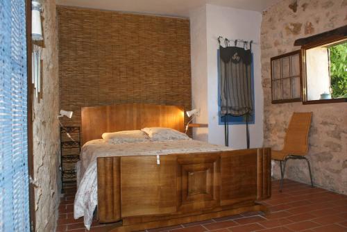 une chambre avec un lit en bois et une chaise dans l'établissement Accommodation in a farmhouse with breathtaking views, à Brignoles