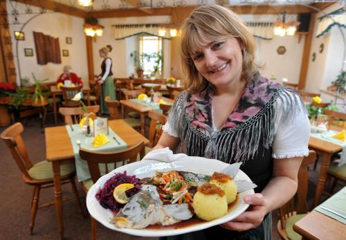 a woman holding a plate of food in a restaurant at Hotel Gasthof zum Walfisch in Klingenthal
