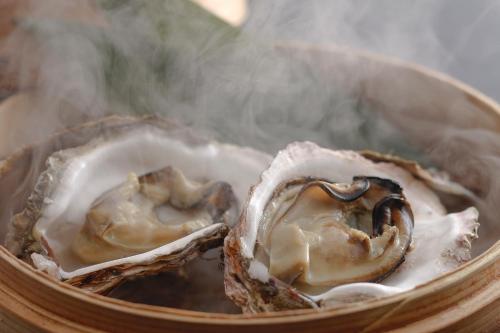 two oysters are cooking in a bowl with smoke at Kasyouen Bettei Fuka - Adult Only in Kyotango