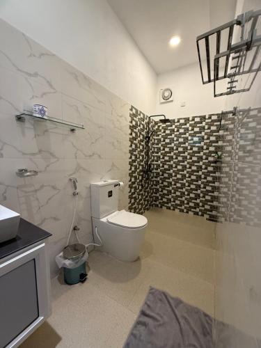 a bathroom with a white toilet and a shower at Devon Surf . Inn - Hiriketiya in Dickwella