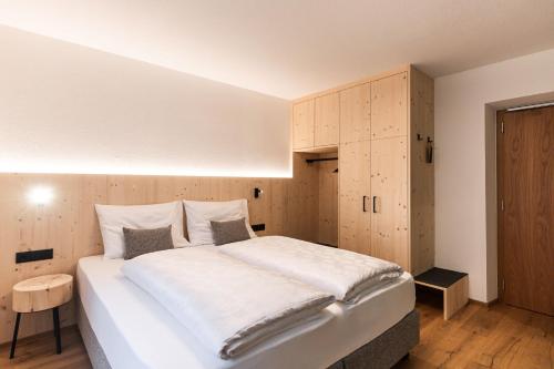 a bedroom with a large white bed and wooden cabinets at Wanderhotel Talblick in San Giacomo