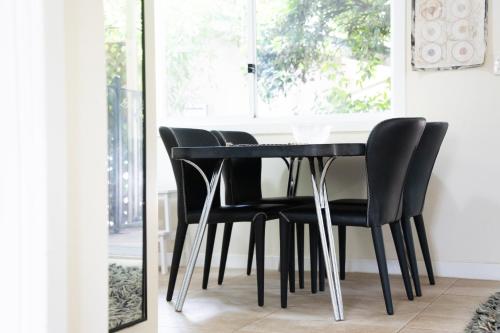 a dining room table with black chairs and a mirror at Farview Guest Accommodation in Pickering Brook