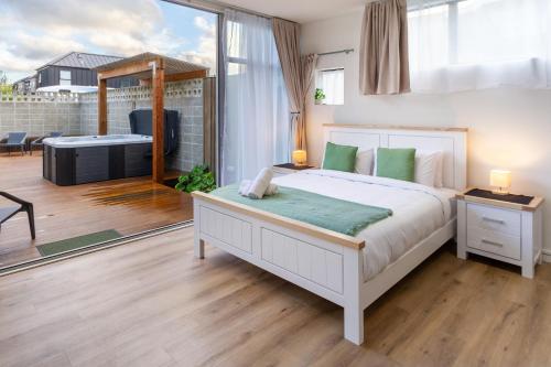 a bedroom with a large bed and a balcony at Luxury King studio with spa and private carpark in Christchurch