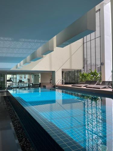 a large swimming pool with chairs in a building at The Grand Wipanan Residence in Chiang Mai