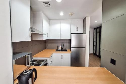 a kitchen with white cabinets and a stainless steel refrigerator at Modern Renovated Studio Building 197 - 5 Min Walking from Metro and Pavilions in Dubai