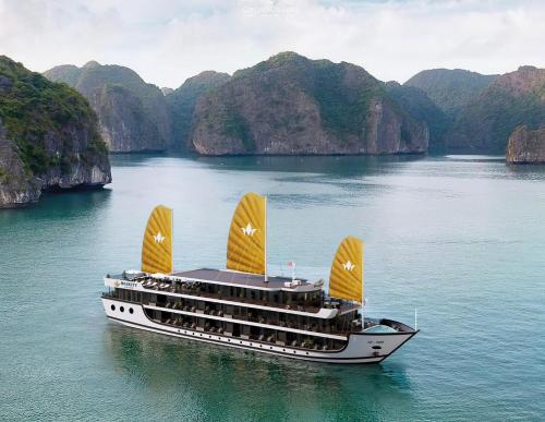 a cruise ship in a body of water with mountains at Majesty Luxury Prime Cruise by Premier Group in Ha Long