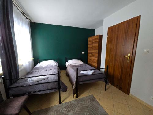 a bedroom with two beds and a green wall at Zamek Międzylesie in Międzylesie