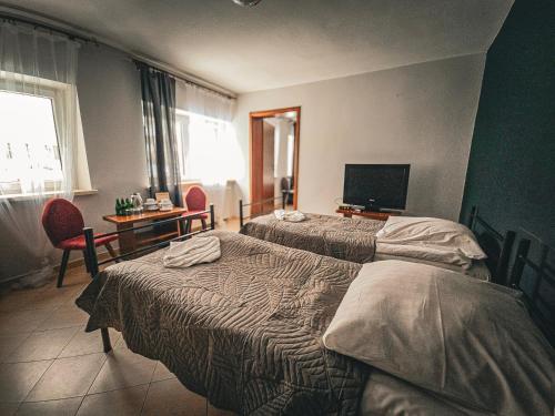 a hotel room with two beds and a desk and a television at Zamek Międzylesie in Międzylesie