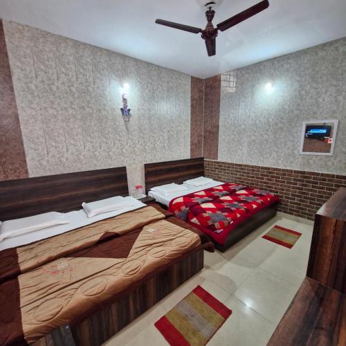 a bedroom with two beds and a ceiling fan at Saatvik Homestay in Katra