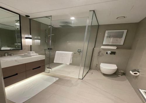 a bathroom with a shower and a toilet and a sink at Bespoke Holiday Homes - Seaside Luxury 2BR in Address Residence, Fujairah in Fujairah